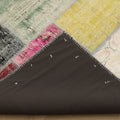 Handmade 6x9 ft vintage Turkish patchwork rug with distressed, vibrant wool and cotton panels and a dark fabric backing.