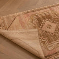 Hand-woven vintage Turkish runner rug in beige and red with geometric patterns, showing wool and cotton texture.