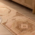 Hand-woven 2x11 ft vintage Turkish runner rug in beige and red with geometric patterns on a wooden floor.