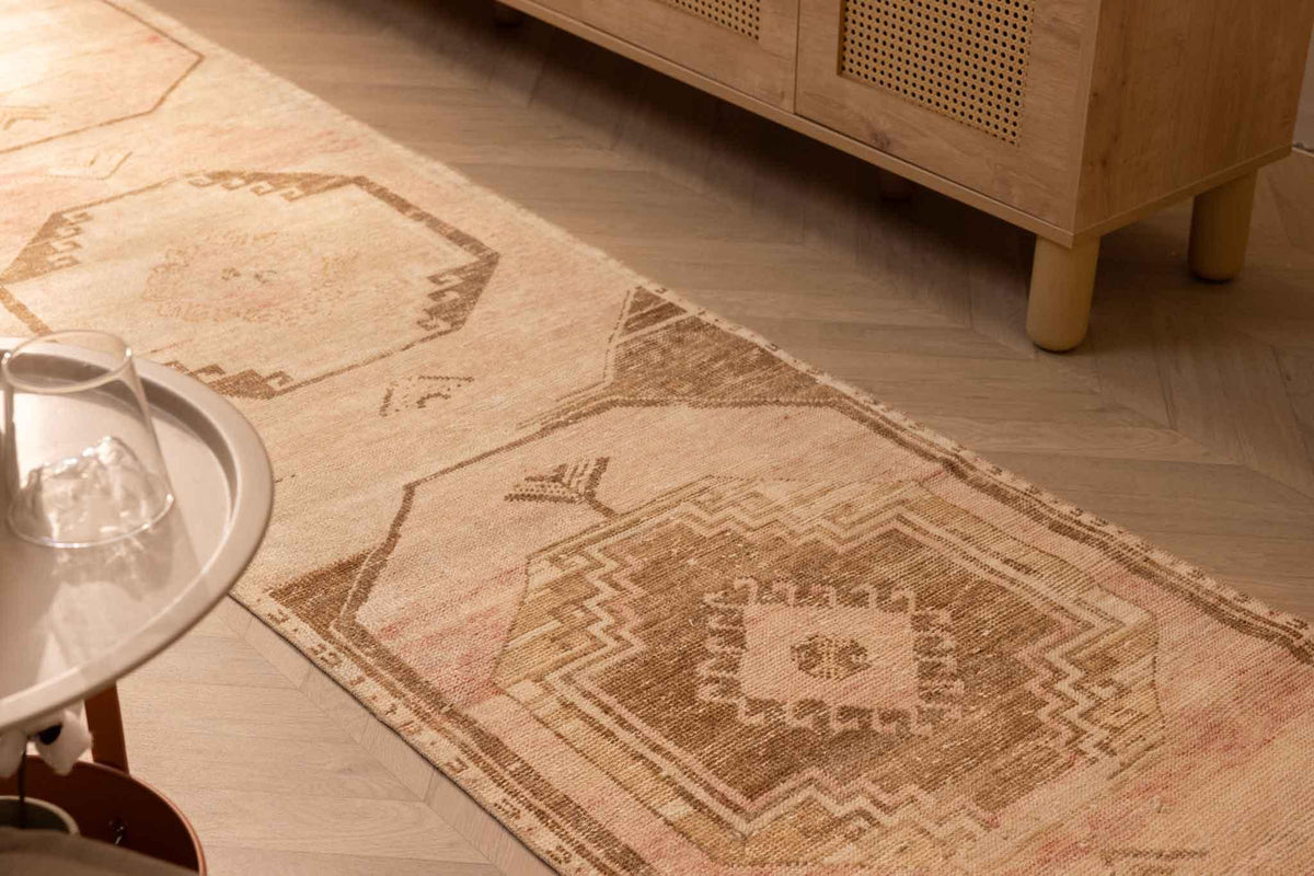 Hand-woven 2x11 ft vintage Turkish runner rug in beige and red with geometric patterns on a wooden floor.