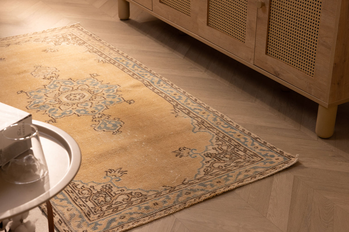 Handmade vintage yellow Isparta Turkish runner rug with floral patterns in wool and cotton on a herringbone floor.