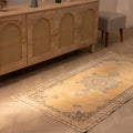 Vintage yellow and beige handmade Turkish runner rug with traditional floral patterns on a wooden floor.