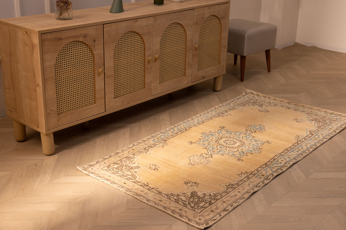 Vintage yellow and beige handmade Turkish runner rug with traditional floral patterns on a wooden floor.