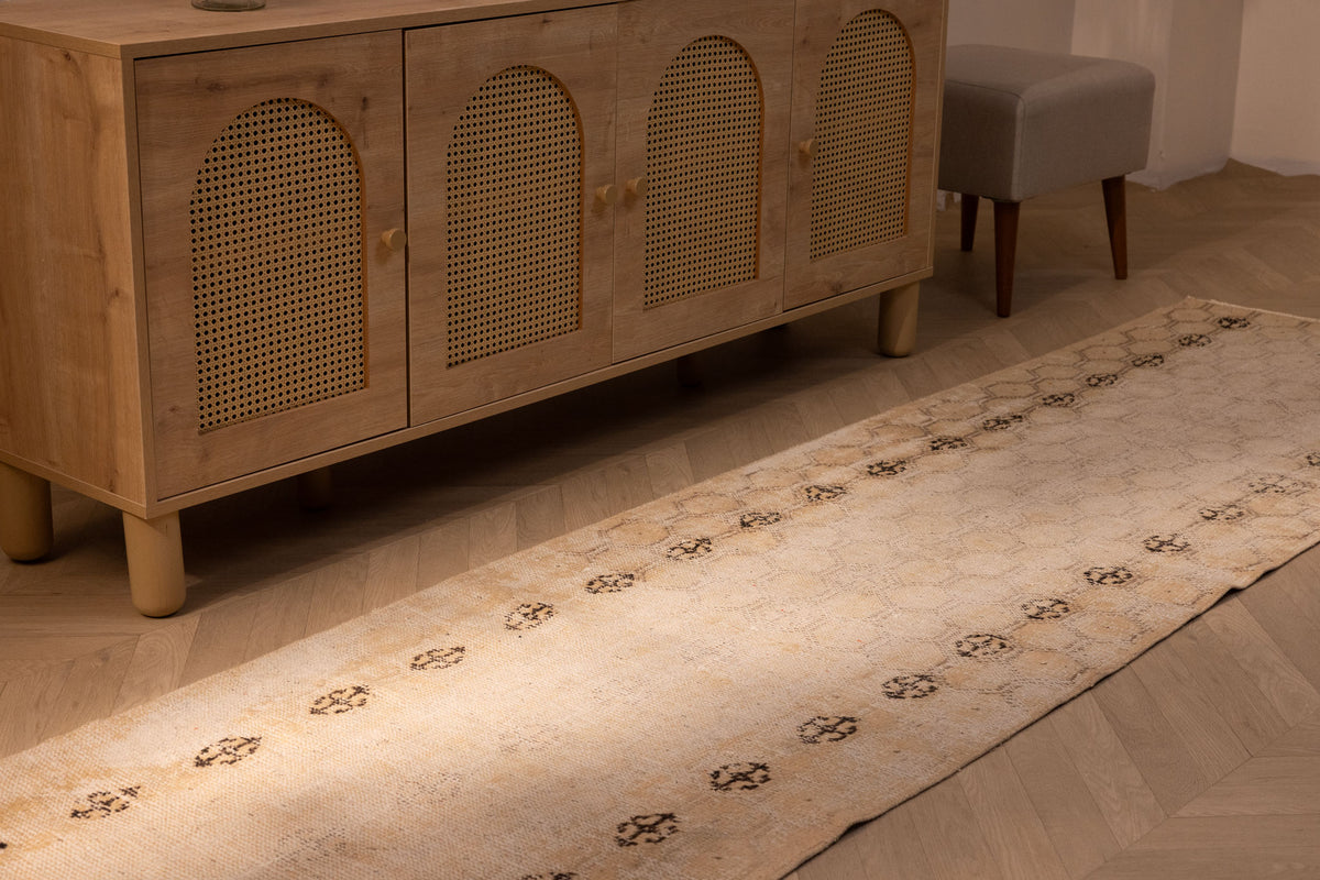Vintage hand-woven 10ft beige Turkish runner rug with geometric patterns in wool and cotton on a wooden floor.