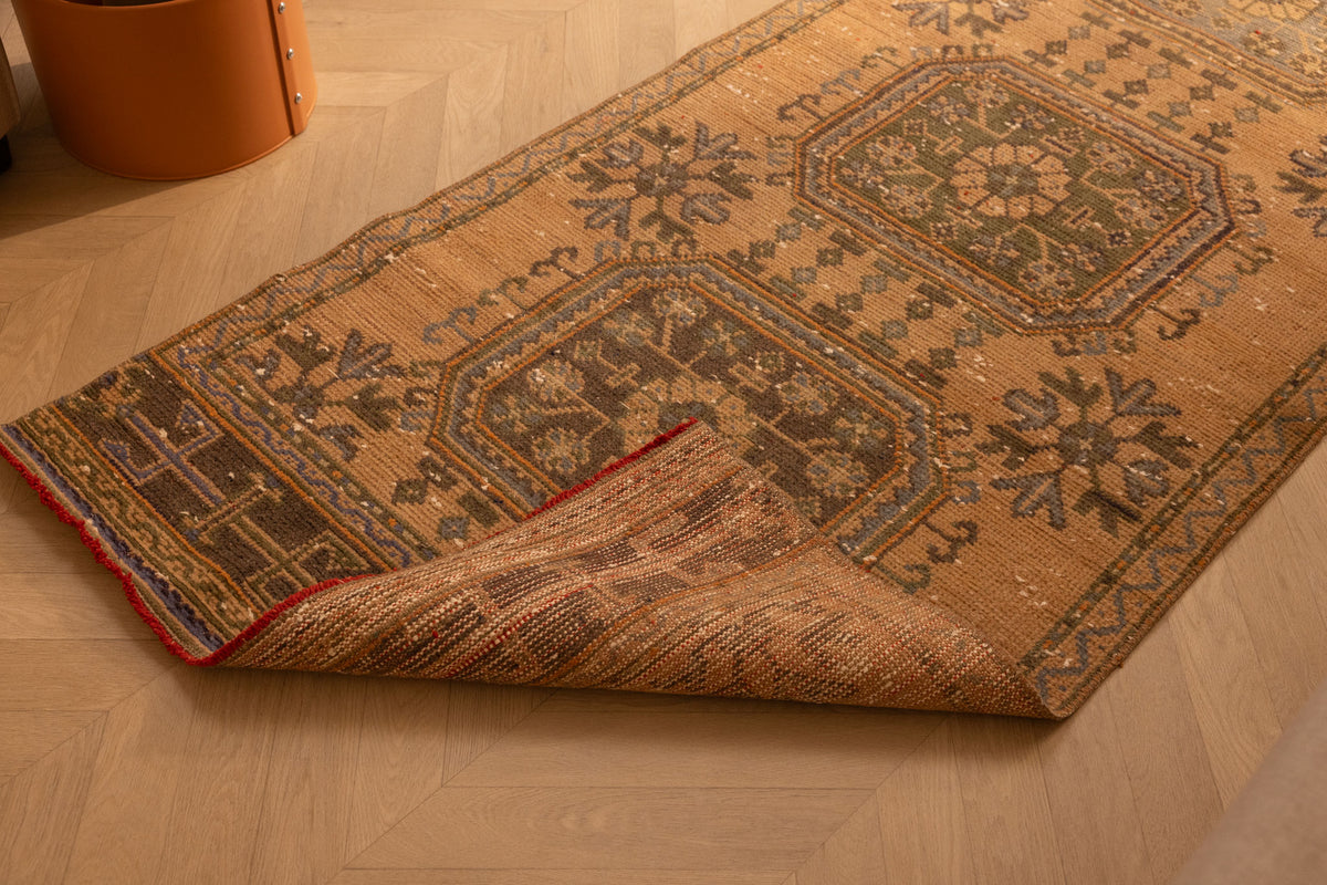 Hand-woven vintage Konya runner rug in beige and brown wool with geometric patterns on a wooden floor.