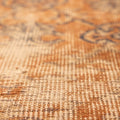 Close-up of a vintage hand-woven Isparta rug in burnt orange with detailed floral patterns and wool-cotton texture.