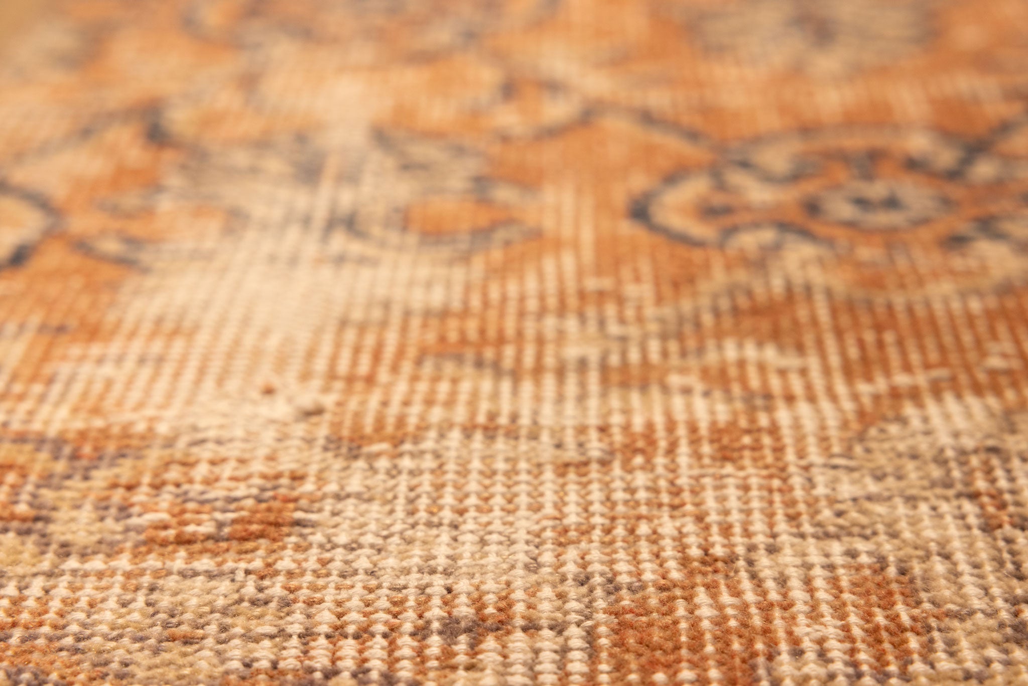 Close-up of a vintage hand-woven Isparta rug in burnt orange with detailed floral patterns and wool-cotton texture.
