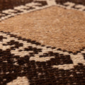 Close-up of a handmade wool and cotton runner rug featuring a white and brown geometric Persian-style pattern.