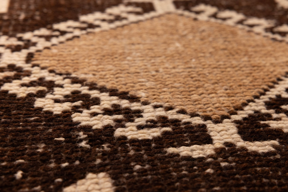 Close-up of a handmade wool and cotton runner rug featuring a white and brown geometric Persian-style pattern.