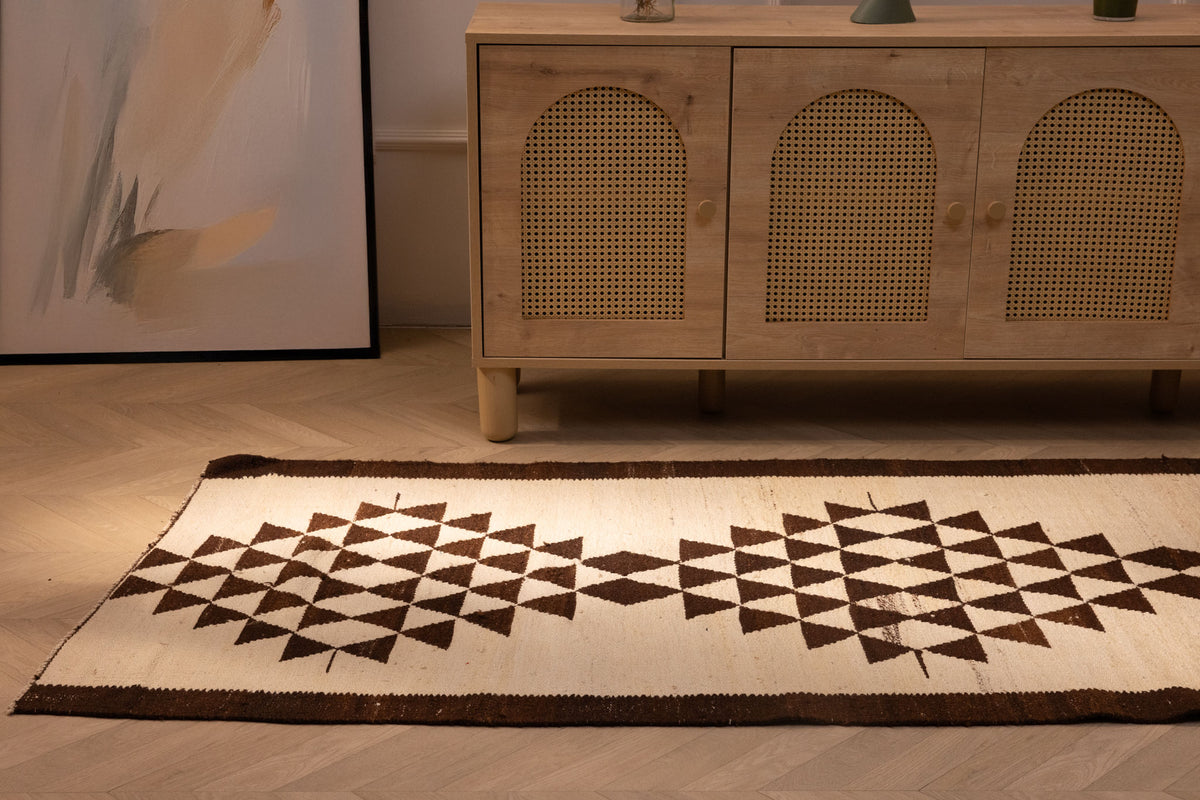 Handmade white and brown wool-cotton Persian-style runner rug with geometric patterns in a farmhouse interior.