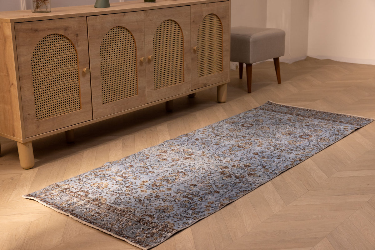 Vintage navy overdyed Turkish runner rug in wool and cotton with a bohemian floral pattern on a wooden floor.