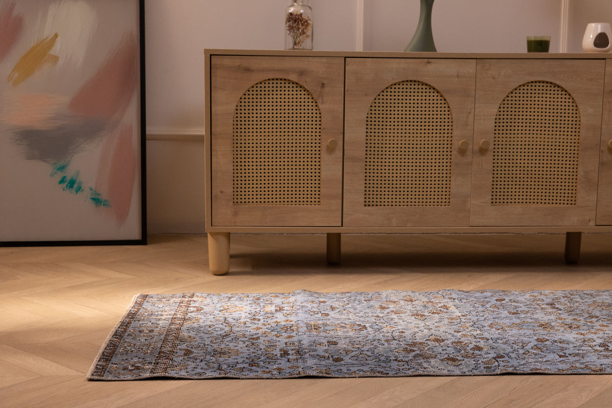 Vintage navy overdyed Turkish runner rug in wool and cotton with bohemian floral patterns on a wooden floor.