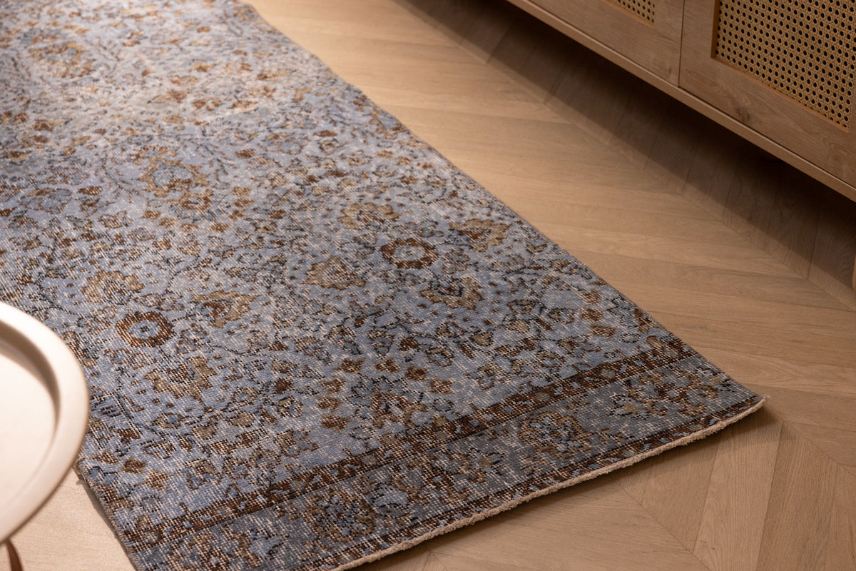 Vintage navy overdyed Turkish runner rug with floral patterns on a wooden floor.