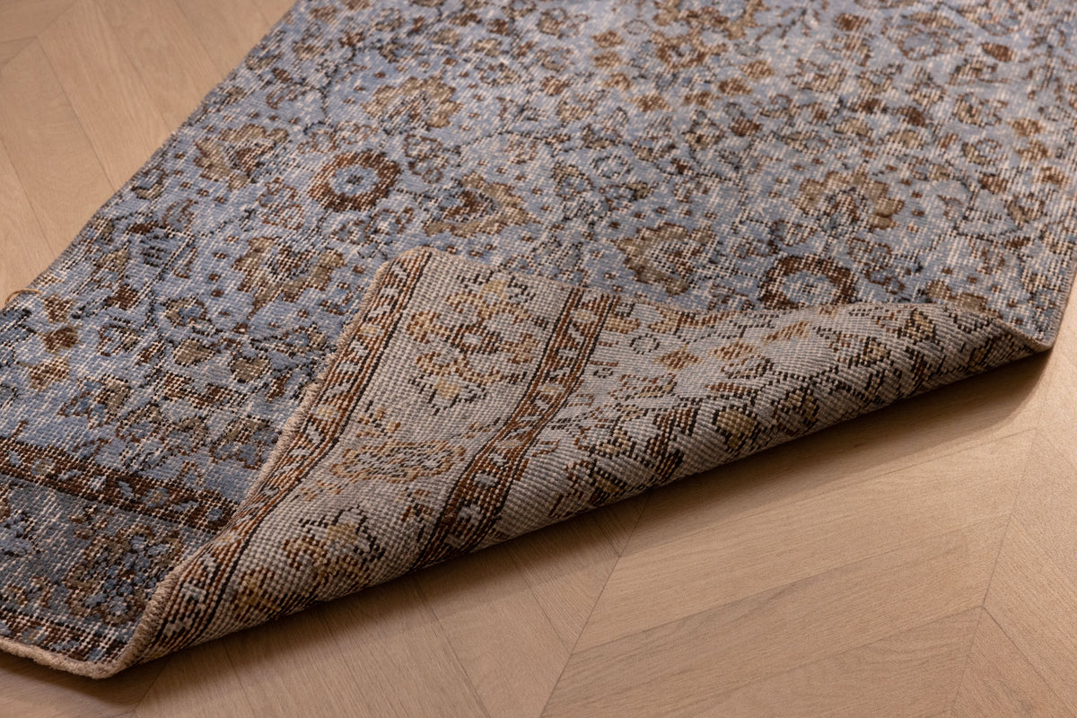 Vintage navy overdyed Turkish runner rug with floral patterns, handmade from wool and cotton on a wooden floor.