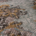 Close-up of a vintage hand-woven Isparta rug featuring brown and gray floral patterns on a low-pile wool and cotton blend.