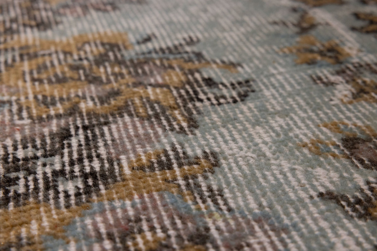 Close-up of a vintage hand-woven Isparta rug featuring brown and gray floral patterns on a low-pile wool and cotton blend.