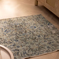 Hand-woven vintage Isparta wool and cotton doormat in gray and navy floral patterns on a wooden floor.