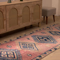 Handmade 3.5x9.9 ft wool and cotton Persian-style runner rug in pink and navy with geometric bohemian patterns.