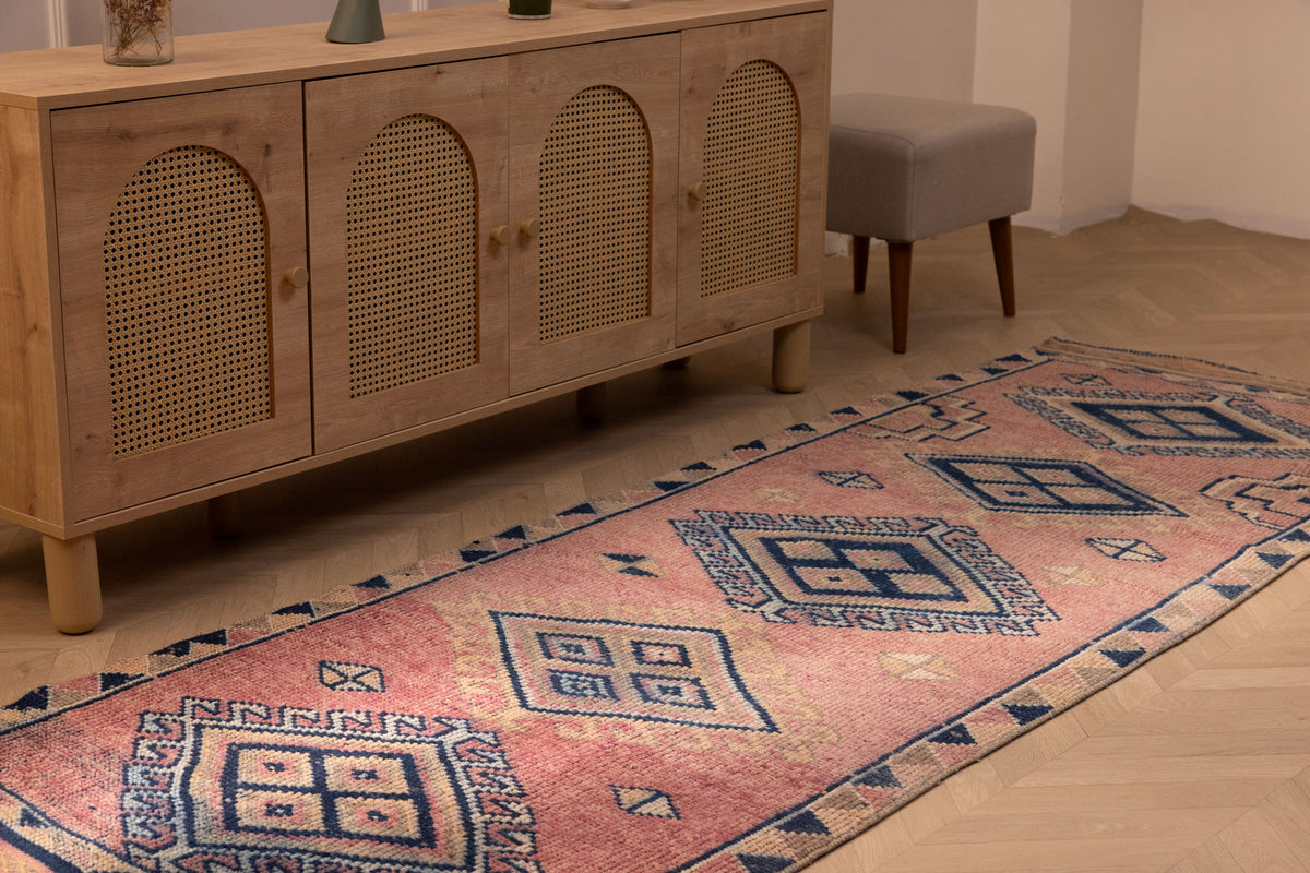Handmade 3.5x9.9 ft wool and cotton Persian-style runner rug in pink and navy with geometric bohemian patterns.