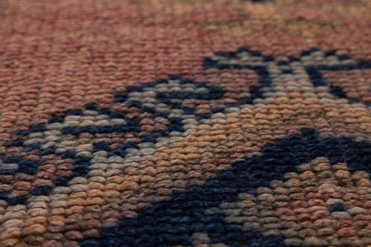Close-up of a handmade wool and cotton Persian-style runner rug with pink and navy geometric bohemian patterns.