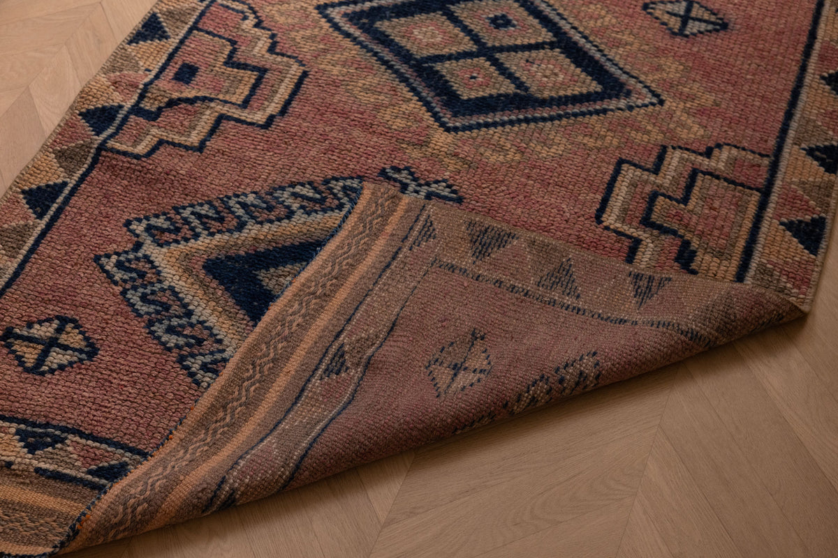 Handmade 3.5x9.9 ft wool and cotton runner rug in pink and navy with bohemian geometric patterns.
