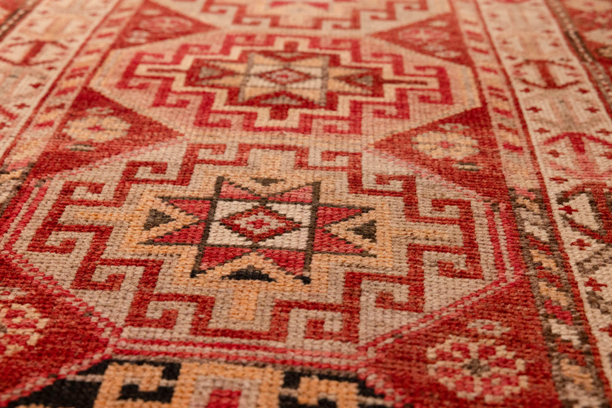 Handmade wool and cotton runner rug in red and brown with geometric bohemian patterns.