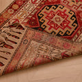 Handmade wool and cotton Persian-style runner rug in red and brown with geometric floral patterns and tasseled edges.