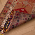 Handmade wool and cotton Persian-style runner in brown and beige with geometric floral patterns and colorful tasseled fringe.