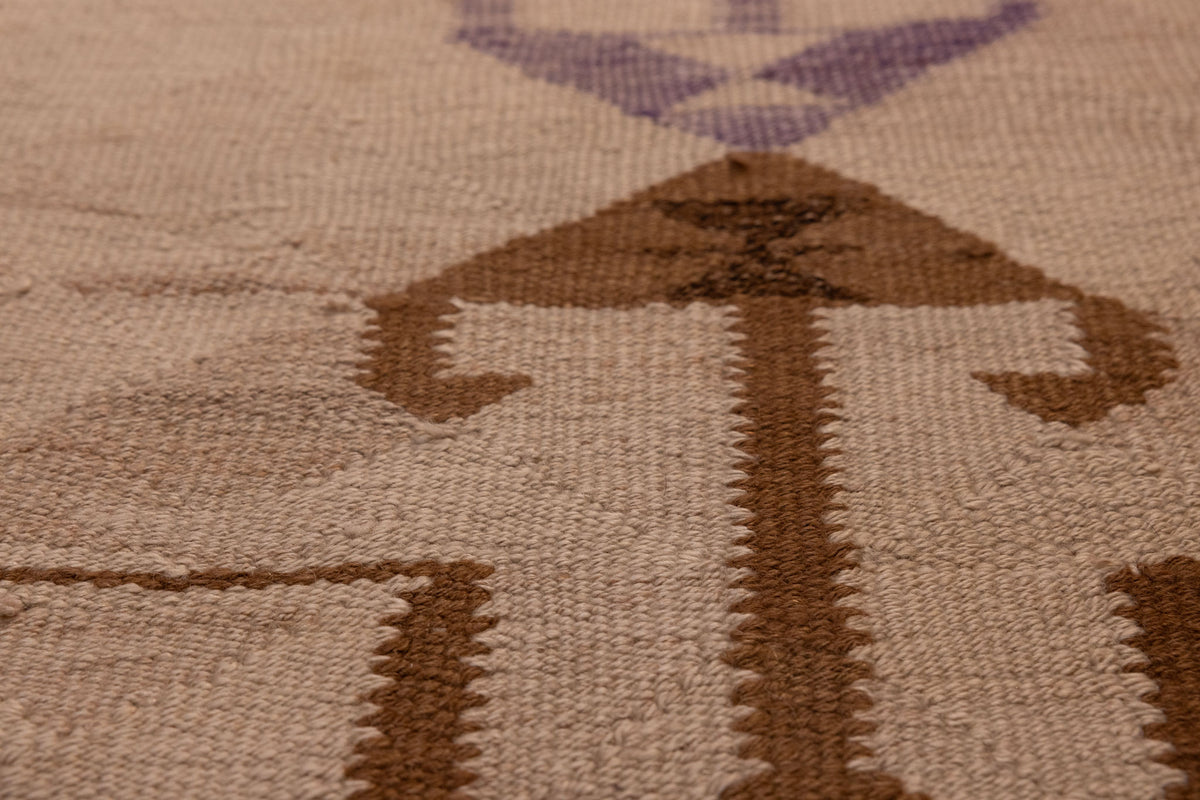 Handmade wool and cotton Persian-style Kilim runner with brown and white geometric patterns in a flatweave texture.