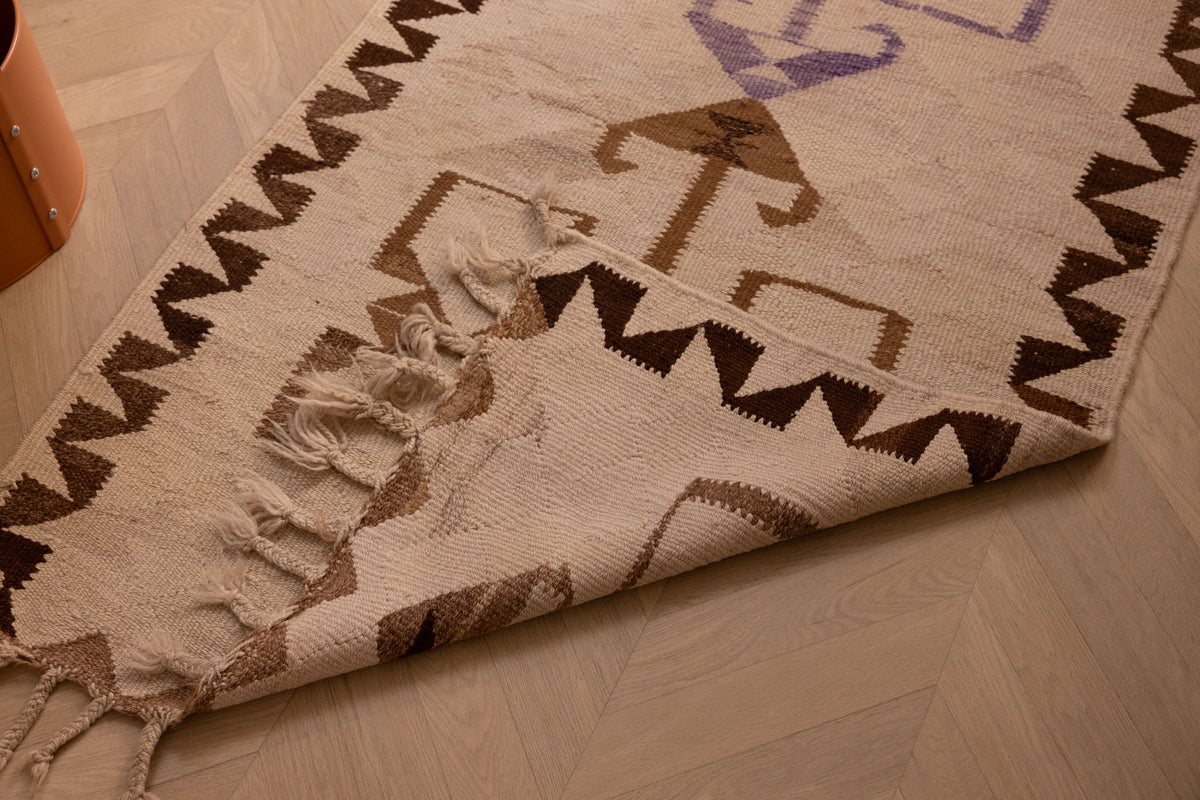 Handmade 3x11 ft wool and cotton Persian-style kilim runner with white and brown geometric patterns on a wood floor.