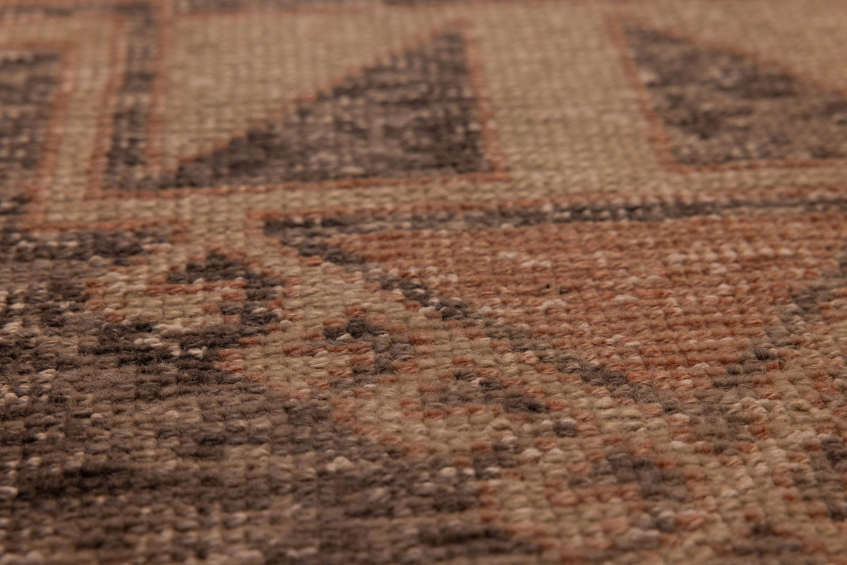 Close-up of a vintage hand-woven Turkish runner rug with orange and gray geometric patterns in wool and cotton.