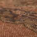 Close-up of a vintage hand-woven Konya runner rug featuring orange and dark floral patterns in wool and cotton.