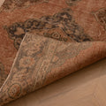 Vintage burnt-orange Konya runner rug with floral motifs, hand-woven in wool and cotton with a folded corner detail.