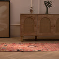 Handmade pink wool and cotton Persian-style runner rug with geometric southwestern patterns in a bohemian room.