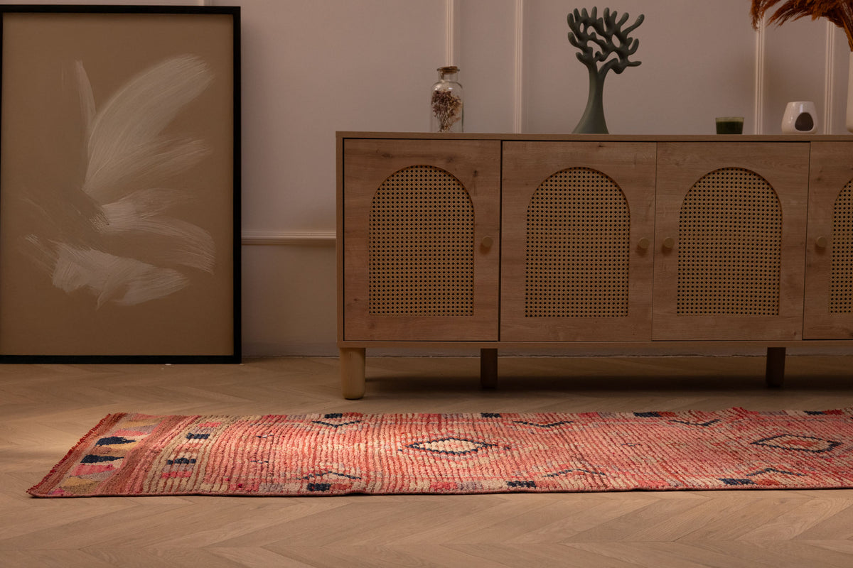 Handmade pink wool and cotton Persian-style runner rug with geometric southwestern patterns in a bohemian room.