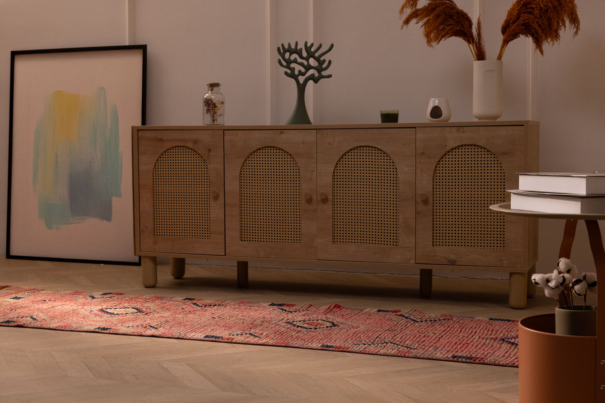 Handmade pink Persian-style wool and cotton runner rug with geometric southwestern patterns in a bohemian living room.