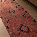 Handmade pink wool and cotton runner rug with bohemian geometric patterns, 2.4 x 10.5 ft, on a herringbone wood floor.