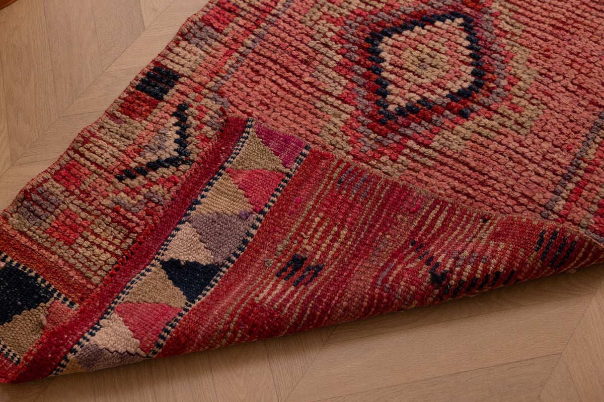 Handmade pink Persian-style wool and cotton runner rug with geometric southwestern patterns.