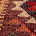 Close-up of a handmade wool and cotton Persian-style Kilim runner with geometric patterns in brown and orange.