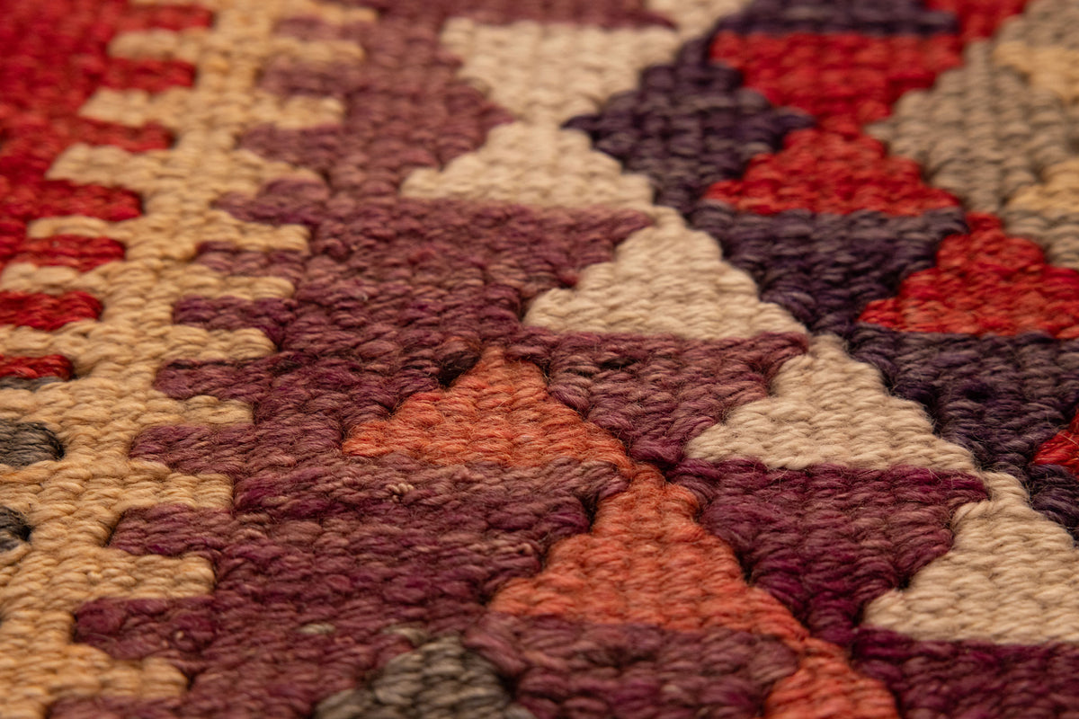 Close-up of a handmade wool and cotton Persian-style Kilim runner with geometric patterns in brown and orange.