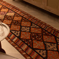 Handmade wool and cotton Persian-style runner rug in brown and orange with a geometric, maximalist bohemian pattern.