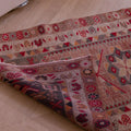 Handmade beige wool and cotton Persian-style runner rug with floral, maximalist patterns and a folded corner.