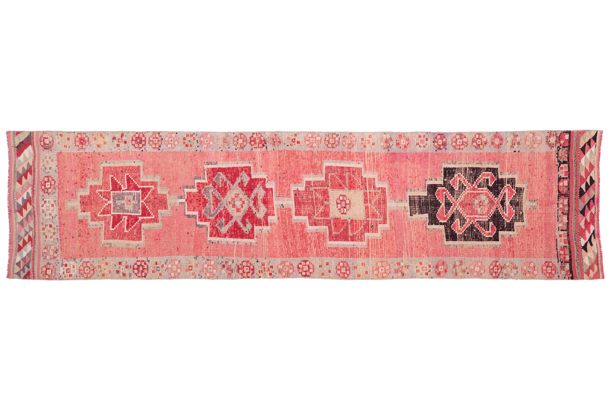 Pink patterned rug with geometric designs on a white background