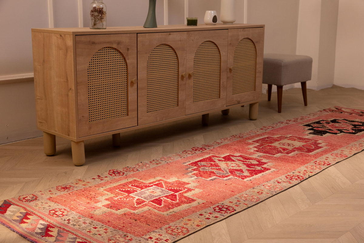 Handmade pink Persian-style wool and cotton runner rug with geometric patterns, 2.9 x 11.1 ft, in a bohemian interior.