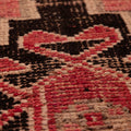 Close-up of a pink and black geometric wool-cotton runner rug with a textured, low-pile bohemian design.