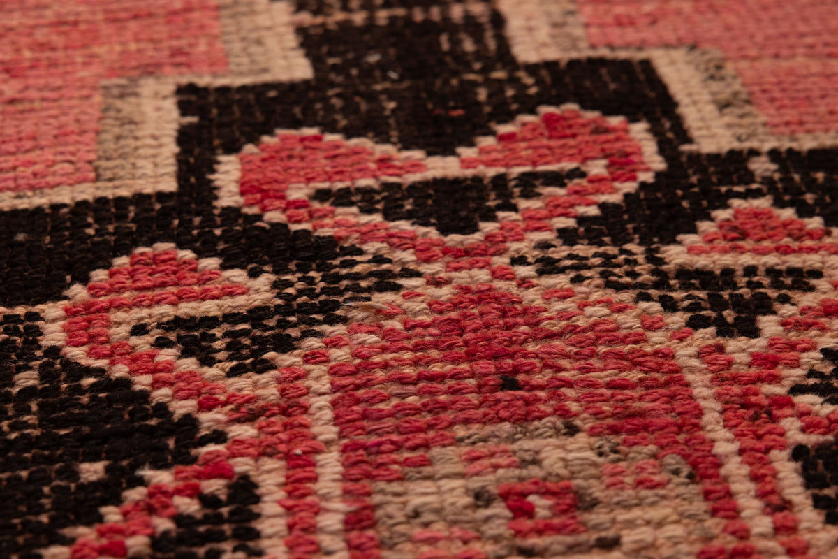 Close-up of a pink and black geometric wool-cotton runner rug with a textured, low-pile bohemian design.