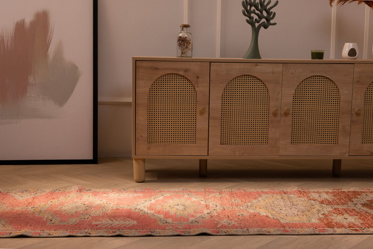Handmade pink and brown Persian-style wool and cotton runner rug with geometric patterns on a wooden floor.