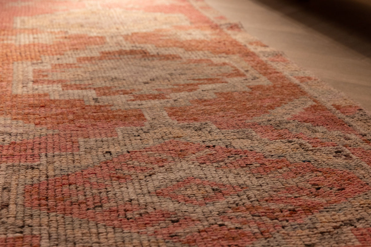 Handwoven pink and brown wool-cotton runner rug featuring geometric patterns in a bohemian Persian style.