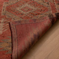 Handmade pink and brown wool-cotton Persian-style runner rug with geometric patterns on a wooden floor.