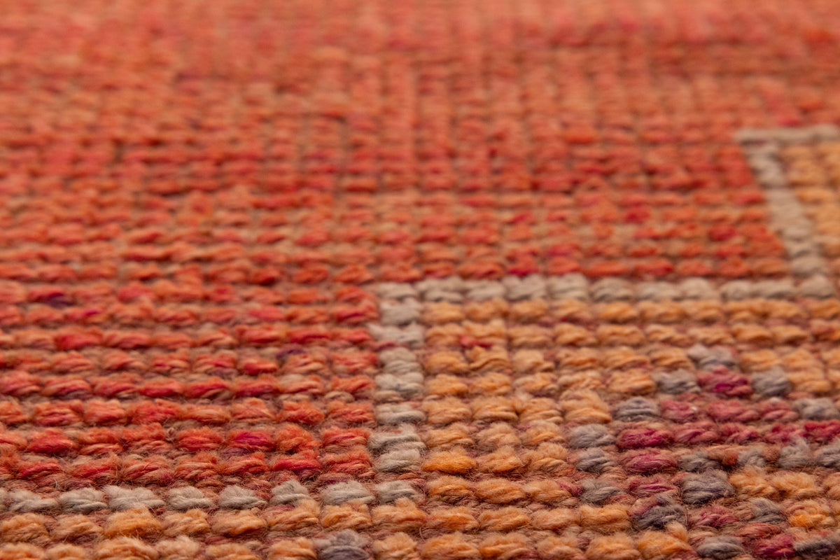Close-up of a handmade wool and cotton Persian-style runner rug with orange floral patterns and a textured low-pile weave.